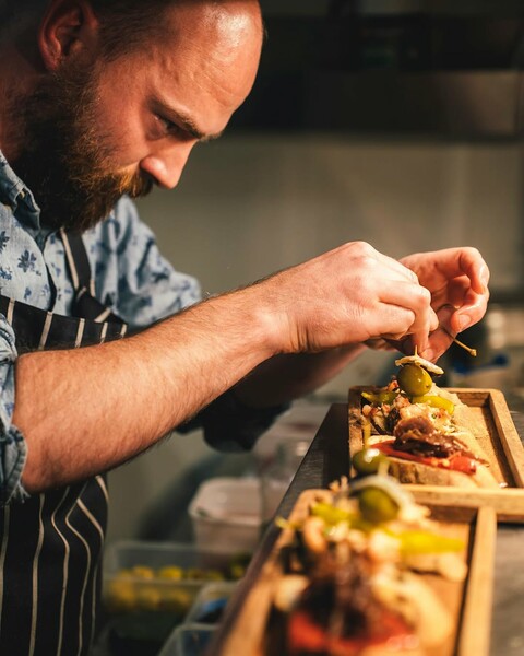 Counter Culture, Newquay, Cornwall — relaxed dining table with small plates, glasses of wine, and vibrant Mediterranean-style cushions — South West regional winner, Best Local Restaurant 2025 in The Good Food Guide.